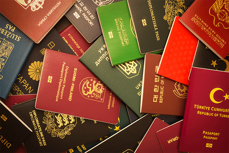 Many passports of various colors are displayed in this image, representing different nationalities
