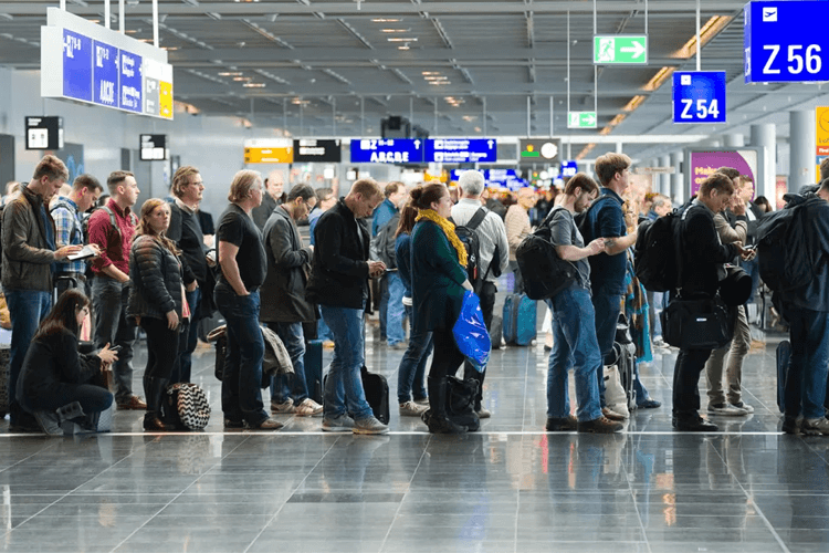 Passengers standing in an orderly queue at the airport, eagerly awaiting their turn to check-in or board their flights