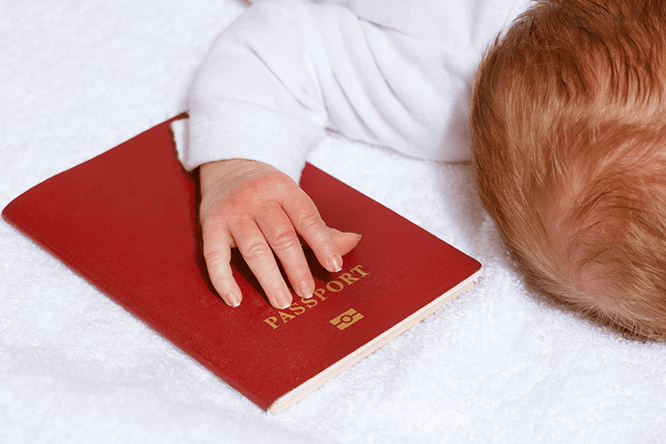 A baby peacefully resting on a bed, holding a passport