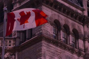 A Canadian flag proudly waving in front of a majestic building